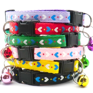 Detail view of colorful fabric pet collars with heart prints, bells and plastic buckles