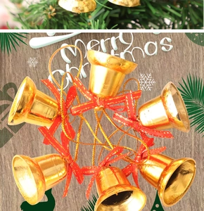 Set of six golden Christmas bells with red silk bows arranged on light wood background