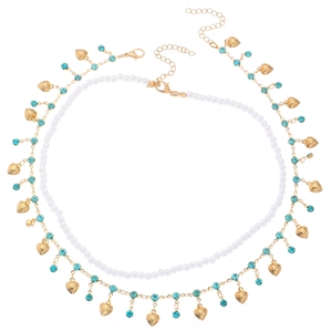 Collier doré multicouche avec perles, pendentifs cœur et strass bleus sur fond blanc
