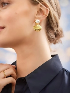 Close-up of golden shell pearl earrings and ear cuffs on a model for a marine style look