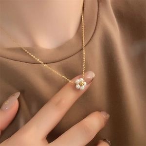 Daisy flower pearl necklace in 18k gold plated titanium steel on female model neckline