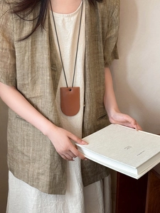 Brown leather magnetic glasses holder necklace shown on a model with a linen jacket