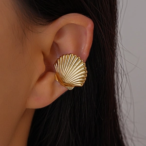 Detail of a polished golden shell ear cuff with radial grooves for non-pierced ears