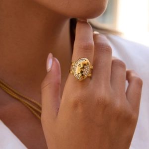 Detail of 18K gold-plated oval locket ring with moon face design and white crystals