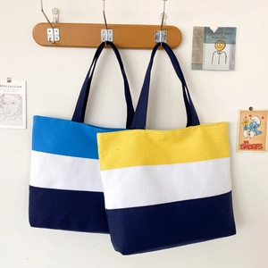 Detail showing two striped canvas tote bags with navy handles hanging on wood hooks