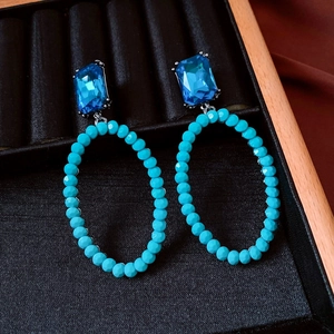 Close-up of vintage oval drop earrings with blue crystal and turquoise beaded hoops