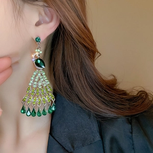Macro shot of peacock tassel earrings with emerald green crystals and sparkling rhinestones