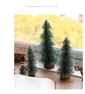 Three mini flocked Christmas trees with snow effect and natural wooden bases on a wooden table
