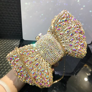 Close-up of golden bow clutch bag with colorful rhinestones and gold chain strap