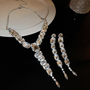 Close-up of sparkling crystal pendant necklace and fringe earrings set on a white tray