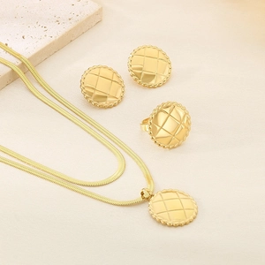 Detailed view of 18K gold plated jewelry set with quilted pattern on beige surface