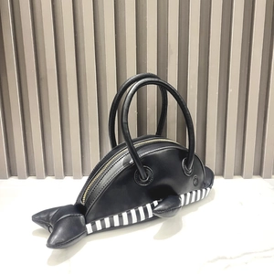 Detail of whale-shaped handbag showing black leather finish and striped belly