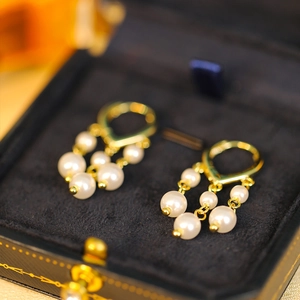 Macro view of gold tassel earrings with pearls on black velvet jewelry display