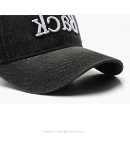 Detail shot of white 'BACK' 3D embroidery and stitching on washed black cotton baseball cap