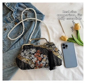 Detail of shell-shaped bag with floral embroidery, pearl chain, and long black tassel