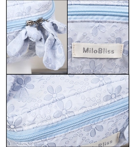 Detailed close-up of floral jacquard fabric and dual zippers on light blue toiletry bag