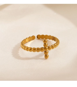 Macro detail of 18K gold plated beaded cross ring on elegant silk fabric background