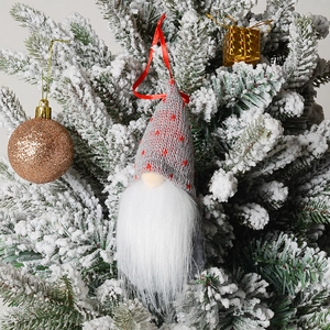 Detail of Christmas gnome pendant with grey star-patterned knitted hat on a snowy tree