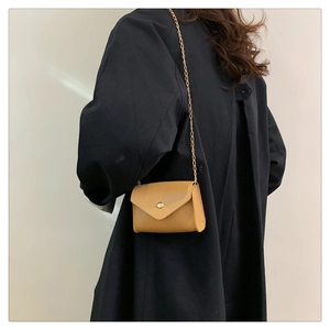 Close-up of brown crocodile texture flap bag with elegant gold chain shoulder strap