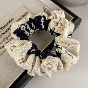 Close-up of vintage navy floral and beige lace scrunchie with 100% cotton tag detail