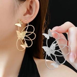 Detail of hollow butterfly and flower earrings in gold and silver finishes on model