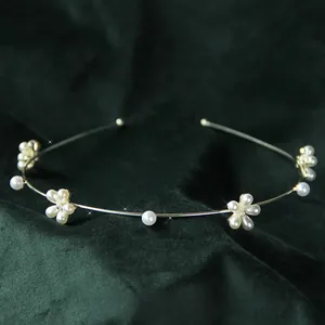 Vista dettagliata di un elegante cerchietto in metallo dorato con fiori di perle bianche
