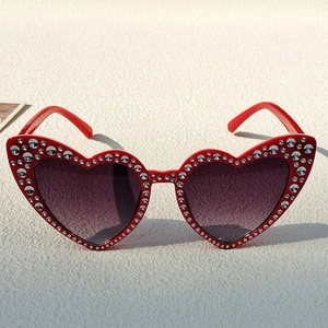 Detail of red heart-shaped kids sunglasses with double rows of sparkling rhinestones