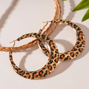 Detail of large gold hoop earrings with leopard print and tropical leaf accents