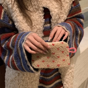 Close-up of plush off-white coin purse with red heart embroidery held in hand