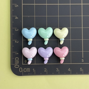 Miniature colorful resin heart charms shown with a ruler for size scale reference