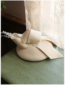 Dettaglio della trama del cappello in feltro avorio con eleganti piume bianche e pieghe