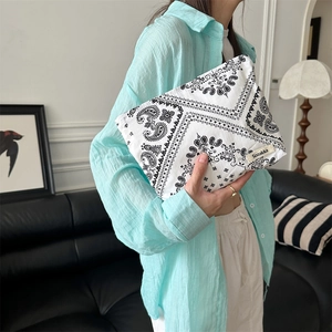 Close-up of model holding the white paisley floral fabric cosmetic bag with Sozakka tag