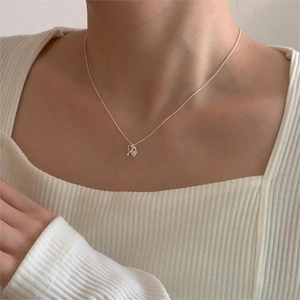 Detail of silver heart key pendant necklace on model's collarbone with elegant finish