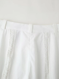 Gros plan détaillé du pantalon blanc avec bordure en dentelle et passants de ceinture