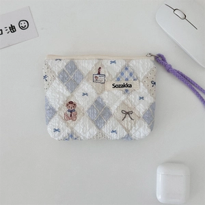 Macro detail of floral quilted makeup pouch with a purple braided rope zipper pull