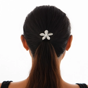 Close-up of a silver flower hair clip with a pearl center worn on a female model