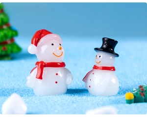 Close-up of mini resin snowmen with red hats and scarves in a creative DIY micro landscape
