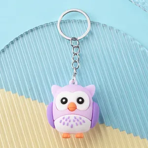 Detail of cute purple owl keychain with silver ring on striped blue and yellow background
