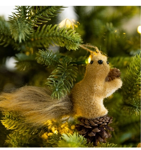 Close-up of a plush squirrel ornament with a pinecone hanging on a Christmas tree branch