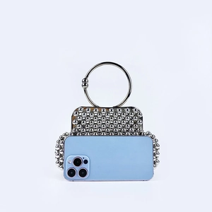 Silver beaded shell handbag with metal ring handle shown with smartphone for scale