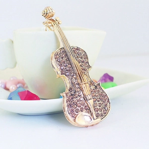 Porte-clés violon doré avec cristaux bruns posé sur une tasse en céramique