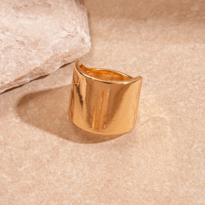 Detailed macro shot of a wide gold metal ring with irregular hammered texture on stone