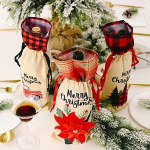 Three-piece burlap Christmas wine bottle bags with plaid accents on festive dinner table