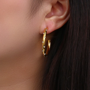 Macro shot of 18K gold plated hoop earrings with inlaid cubic zirconia on a model