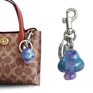 Blauw-paarse verloop paddenstoel tashanger met parelketting op een leren handtas