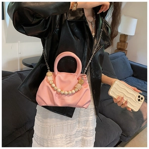 Close-up of pink pleated cloud bag with elegant pearl handle and metal chain strap