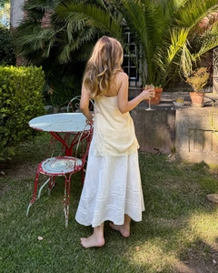 Elegance detail of a beige lace camisole paired with a white skirt in a garden setting