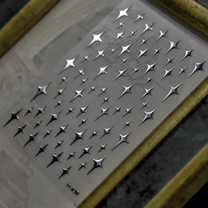 Macro detail of silver 3D laser nail stickers with star patterns in a gold frame