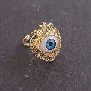 Detailed macro of a 18K gold open ring featuring a blue evil eye inside a heart shape