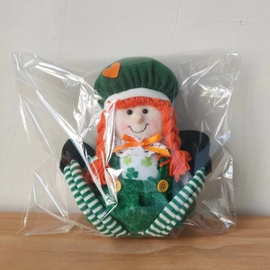 Detailed fabric texture of St. Patrick's doll with green clover patterns and orange braids